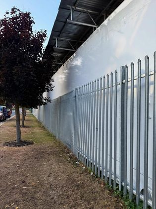 Wrapped structure behind palisade fencing