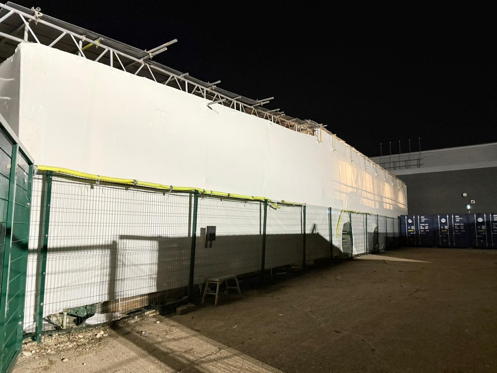 Temporary structure fully shrink wrapped at night